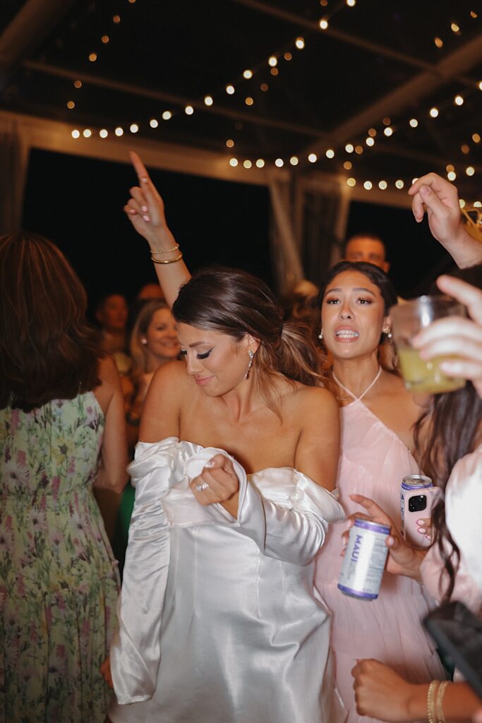 A bride dances with her guests around her during an outdoor reception