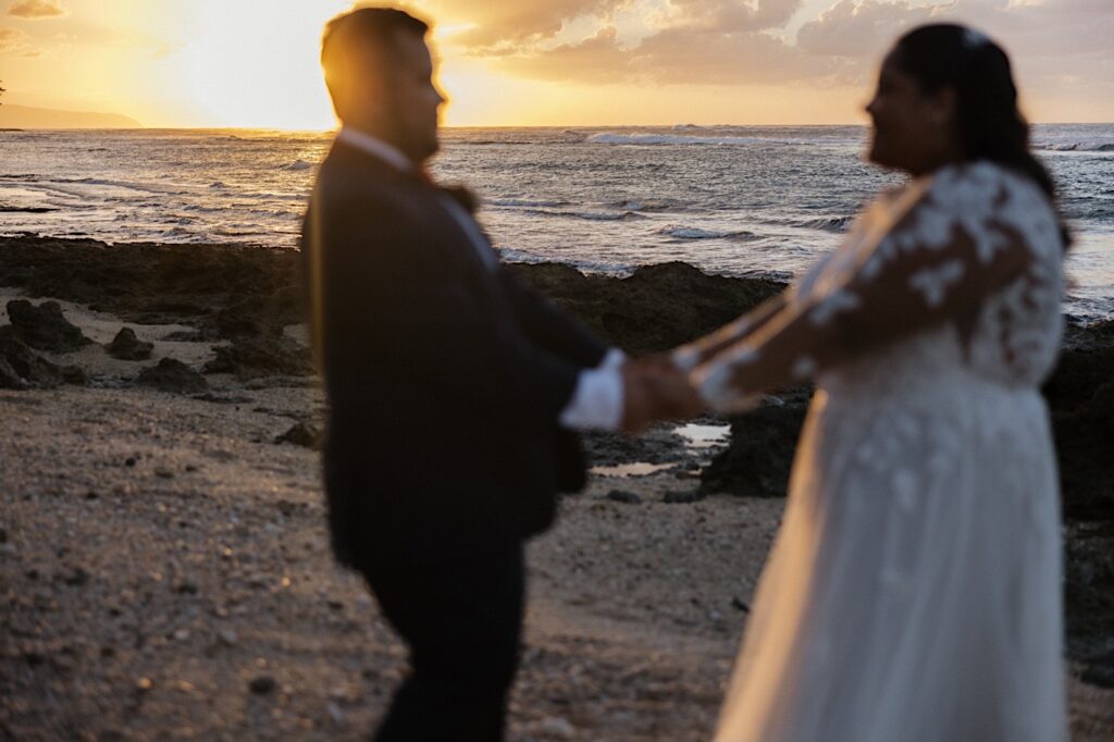 A bride and groom dance on the beach at sunset after their wedding ceremony at a villa on Oahu