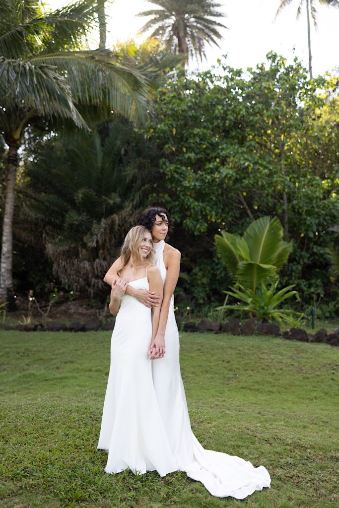 2 brides pose for a portrait photo together on the lawns of Loulu Palm on Oahu
