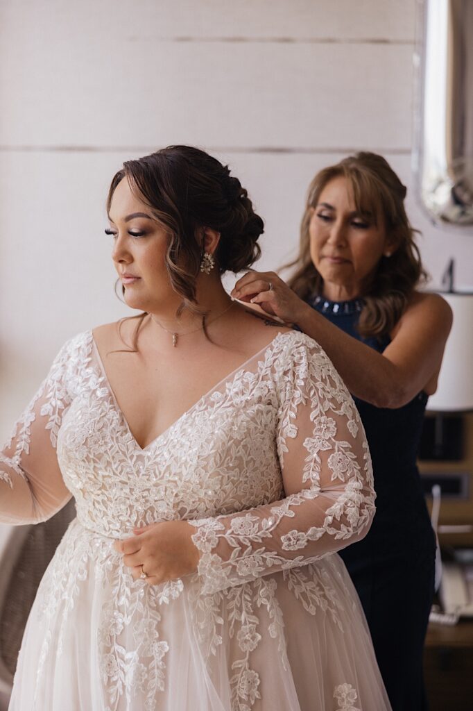 A bride has her mother help put the finishing touches on her as she gets ready for her wedding day