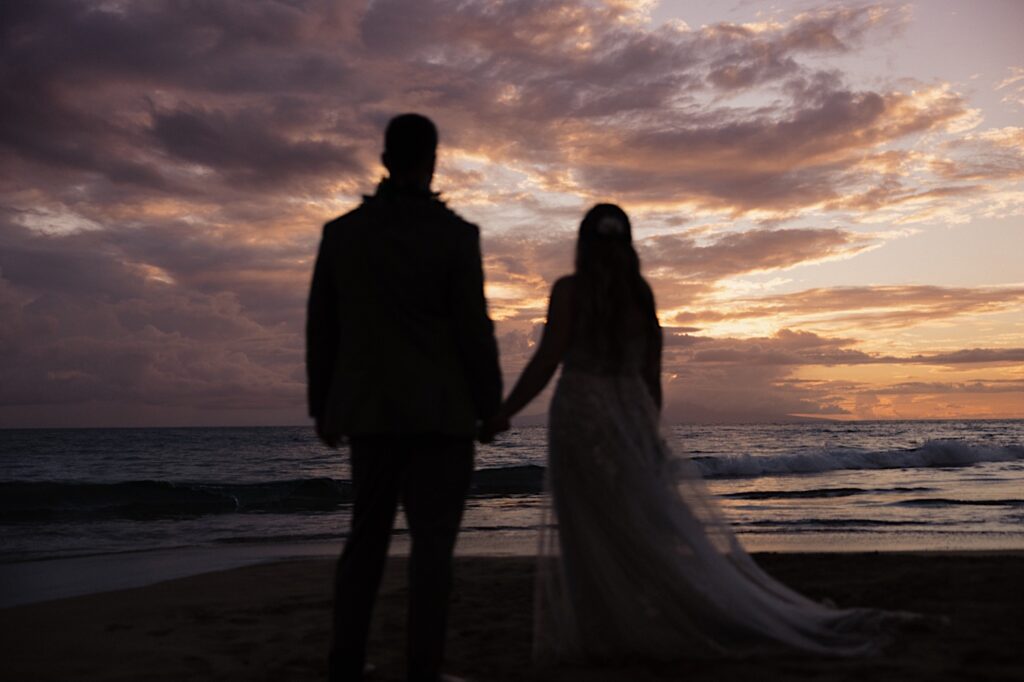 Bride and Groom look off into the ocean and sunset after beautiful ceremony in Maui Hawaii. 