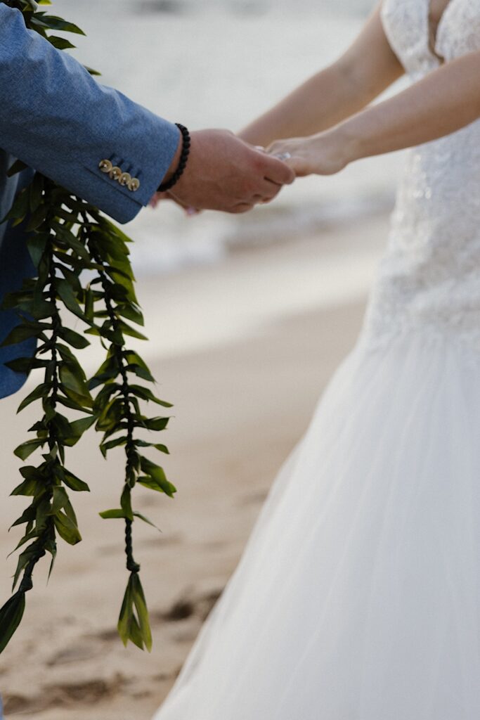 Couple holds hands during elopement wedding ceremony in Maui Hawaii. 