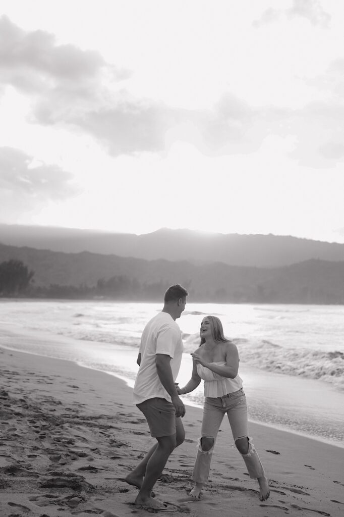 A man in a white shirt plays on a Hawaiian beach resort with his wife in a white blouse with jeans. 