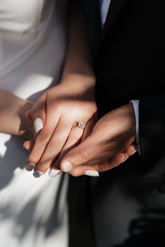 Hawaii Wedding Photographer captures close up of Bride and Groom's hands and Bride's beautiful diamond ring on a gold band outside Wedding Chapel in Four Seasons Oahu in Hawaii. 