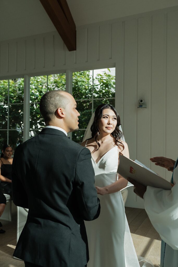 Bride and Groom look at officiant as he speaks during intimate wedding ceremony at Four Seasons Oahu in Hawaii. 