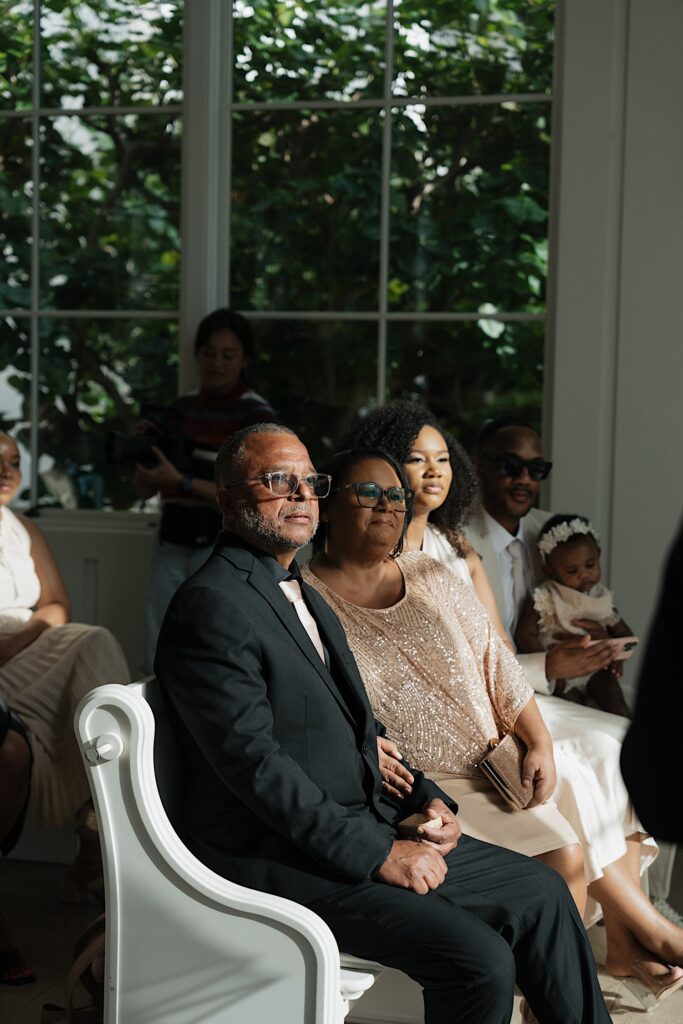 Family of Groom watches bride and groom getting married in intimate wedding ceremony at the Four Seasons Oahu in Hawaii. 