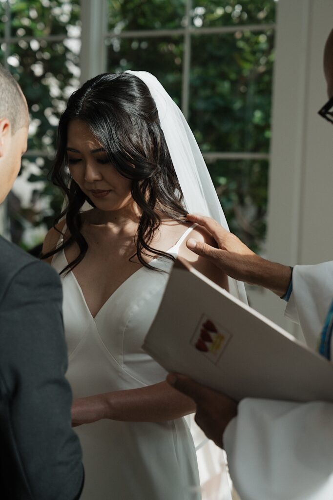 Bride gets emotional as Groom places ring on her finger during intimate wedding ceremony at Four Seasons Oahu Chapel in Hawaii.