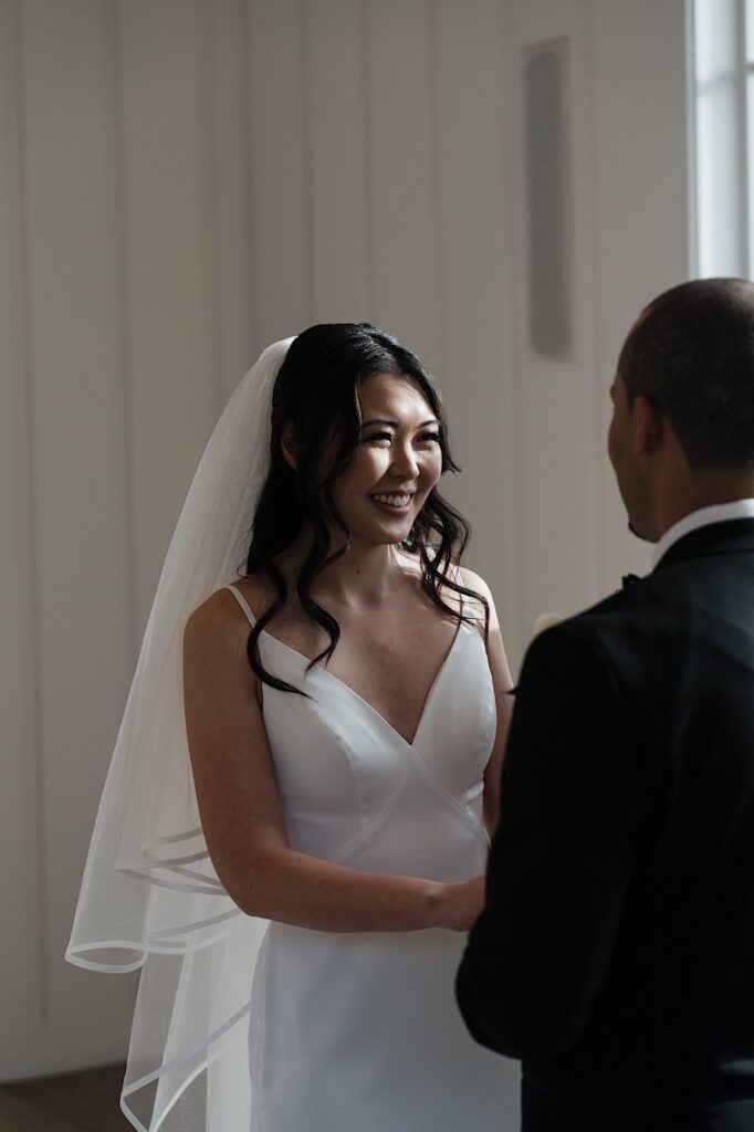 Bride smiles at Groom during intimate wedding ceremony in chapel at Four Seasons Oahu in Hawaii. 