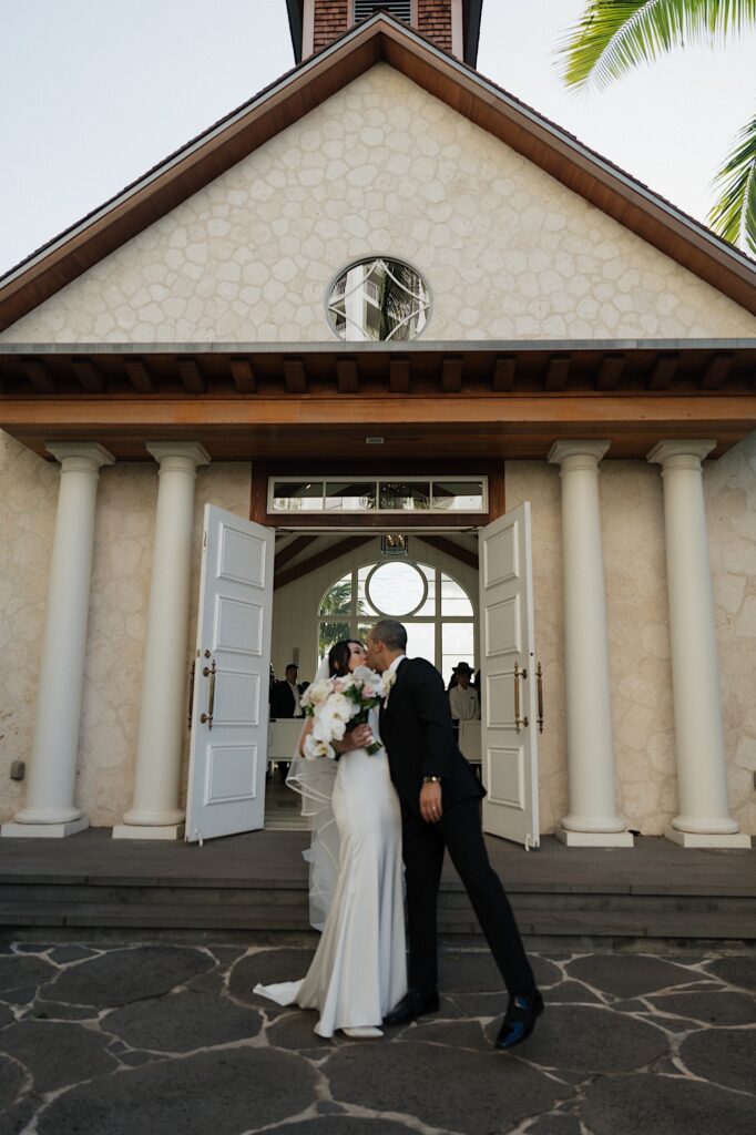 Bride and groom kiss outside intimate chapel at Four Seasons Oahu in Hawaii.