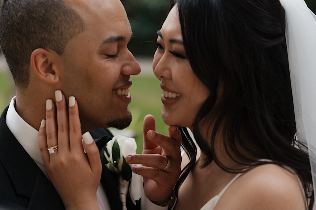 Bride and groom touch each other's faces while looking into each other's eyes in an intimate wedding portrait at the Four Seasons Hawaii in Oahu. 