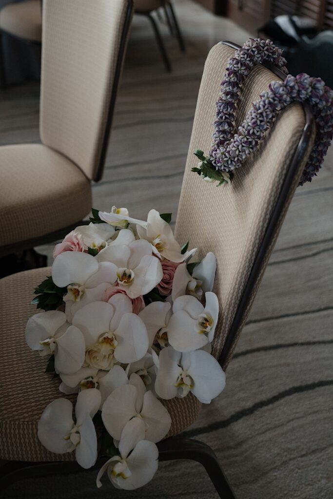 Bride's tropical lei bouquet sits on chair at wedding reception at Four Seasons Oahu in Hawaii. 