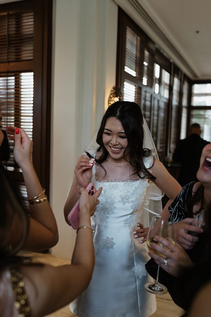 Bride in short floral white dress greets guests at wedding reception at Four Seasons Oahu in Hawaii. 