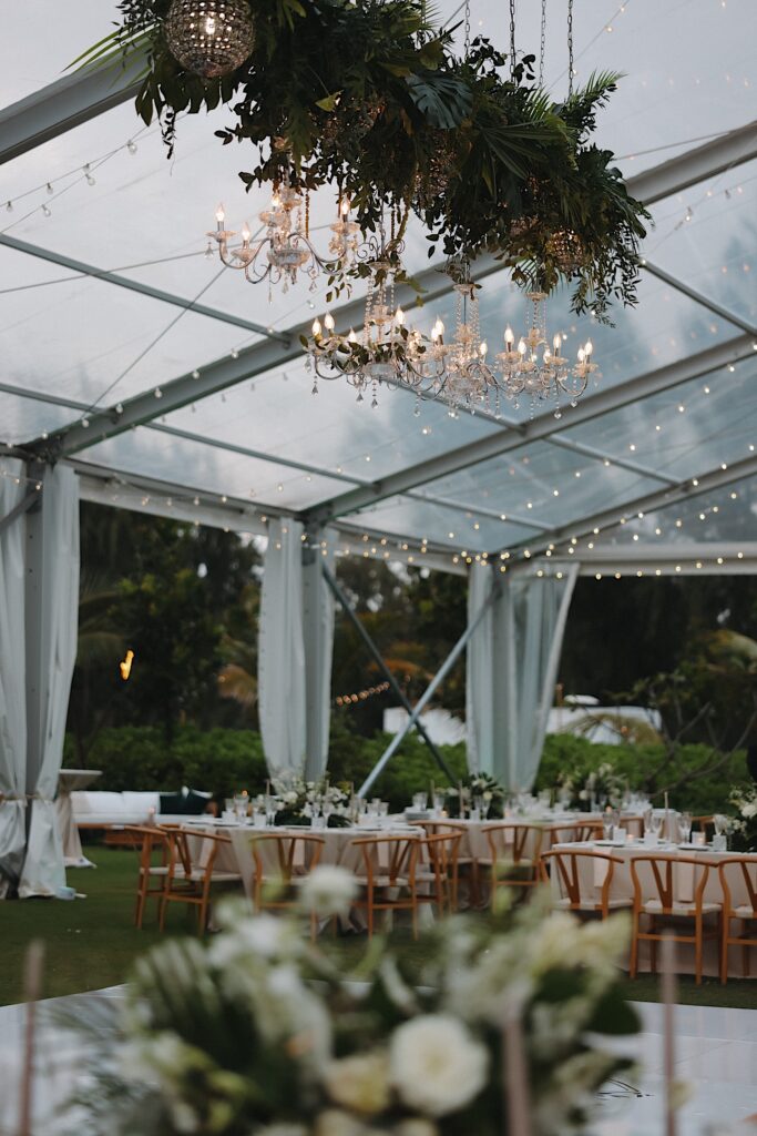 Clear tent with chandeliers hanging from the ceiling for reception venue in Oahu, Hawaii.