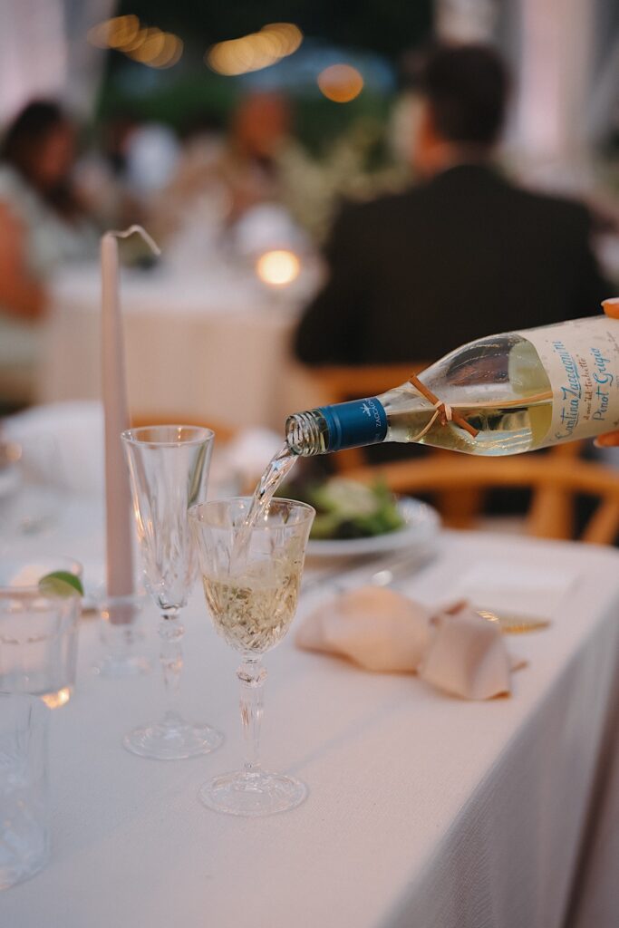 White wine being poured into crystal wine glass on reception table in Oahu Hawaii.